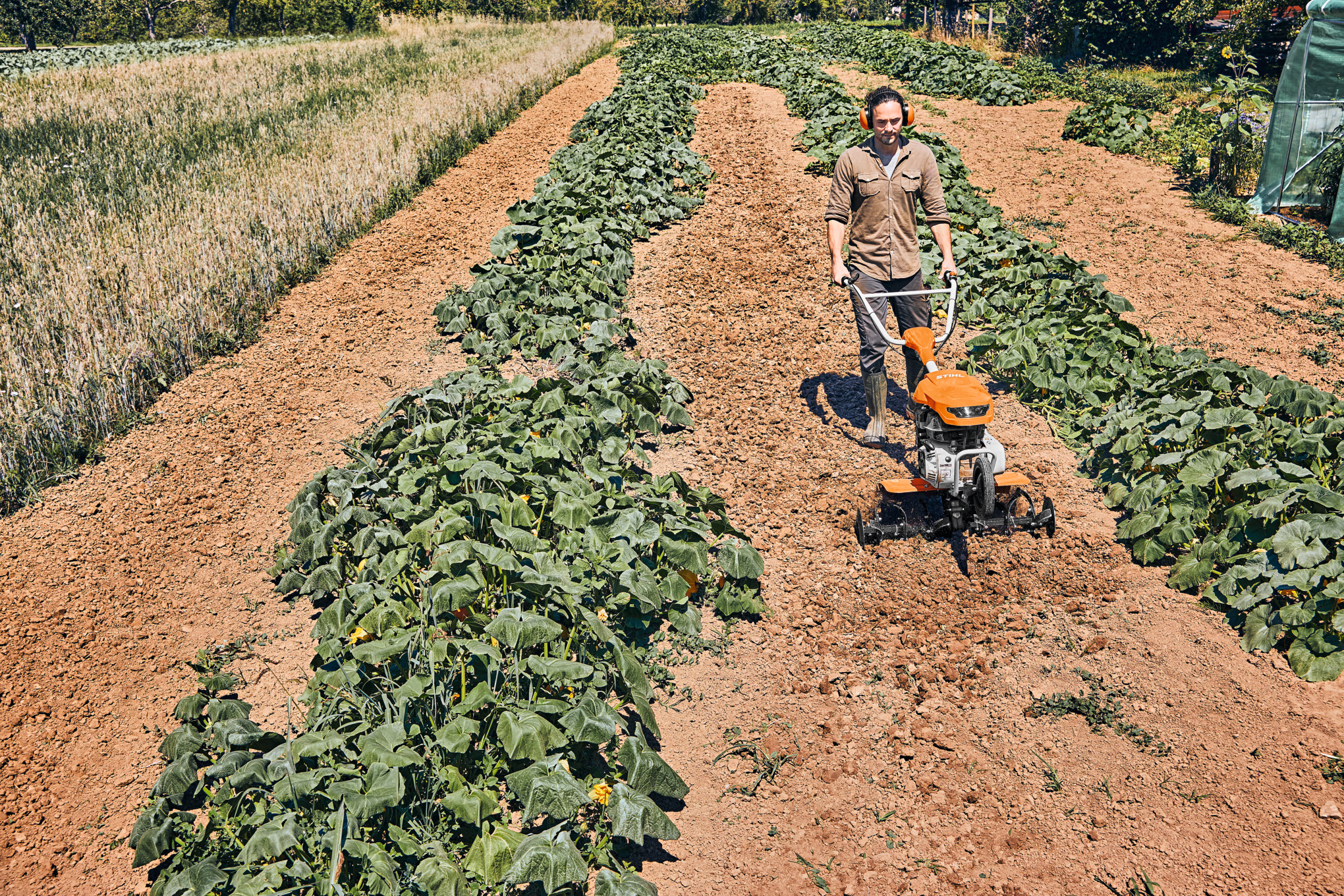 Homme utilisant une tarière dans un champ