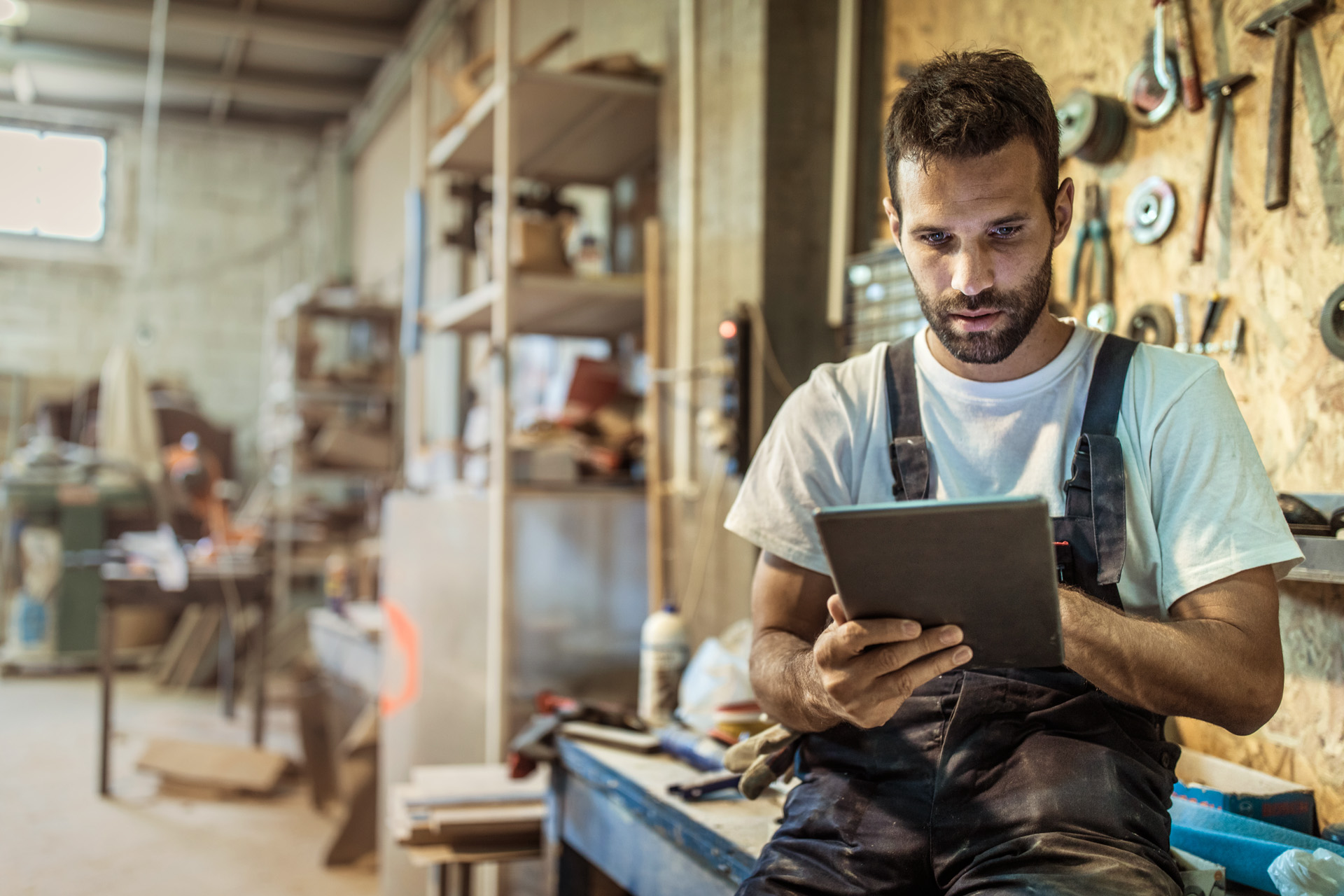 Un revendeur dans un atelier utilise un guide d'achat sur tablette pour choisir des produits et accessoires STIHL.
