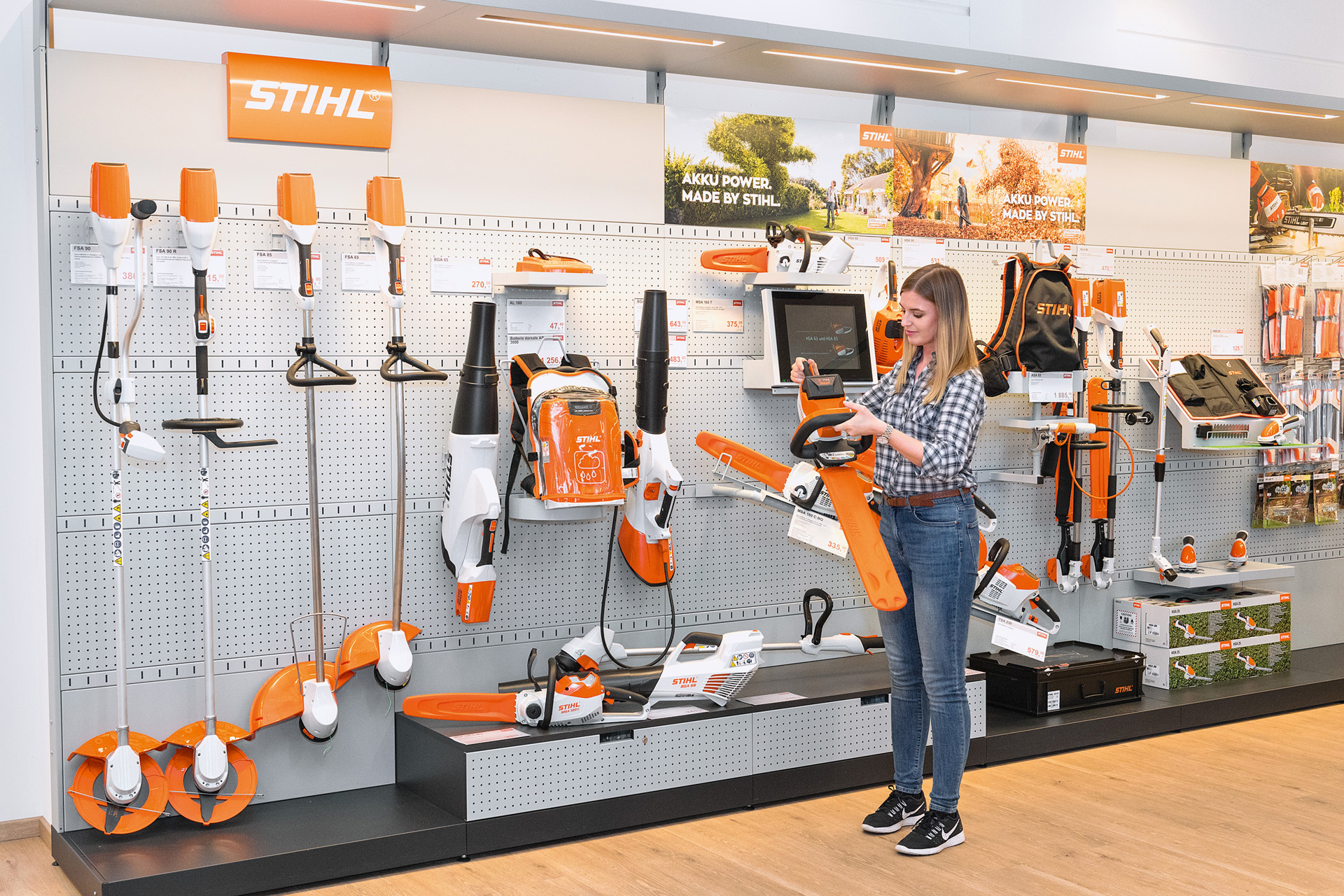 Jonge vrouw voor een rek bij een STIHL dealer wil een STIHL kettingzaag testen