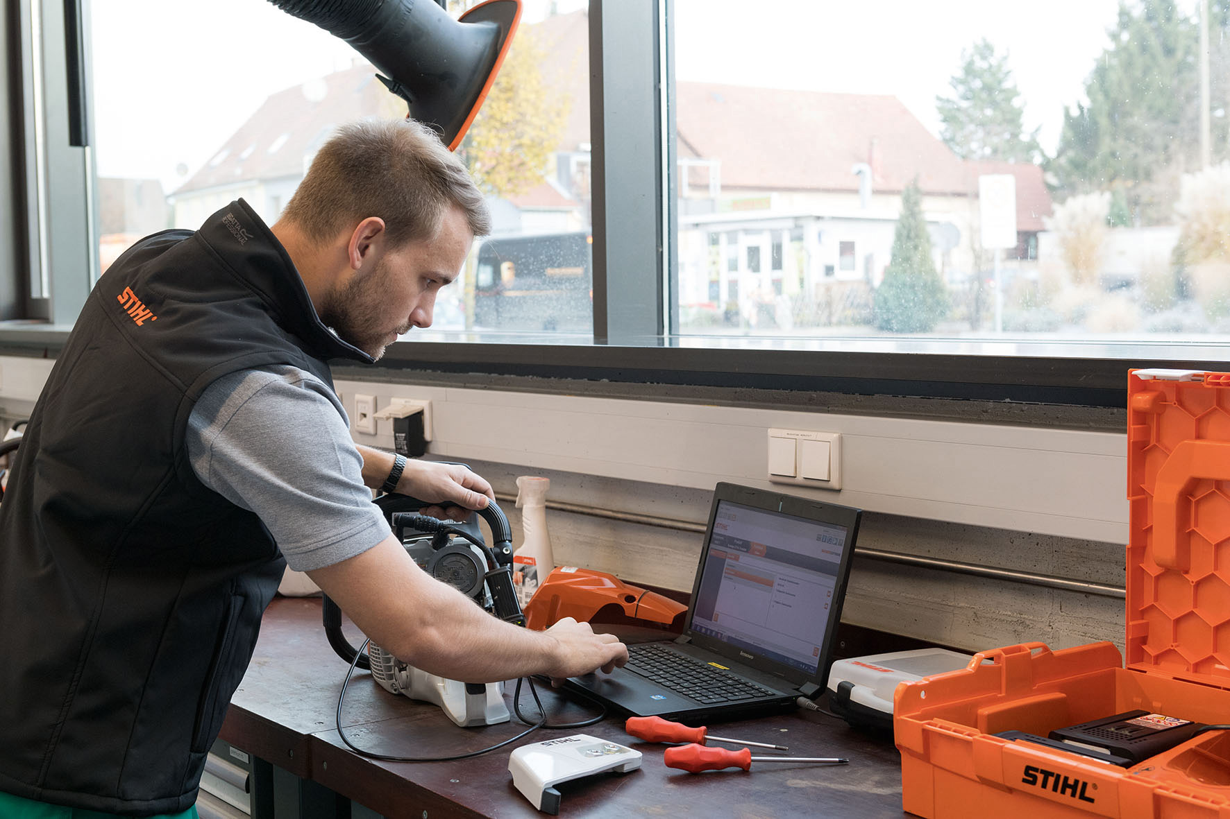 Een man kijkt op een laptop met naast zich een STIHL kettingzaag.