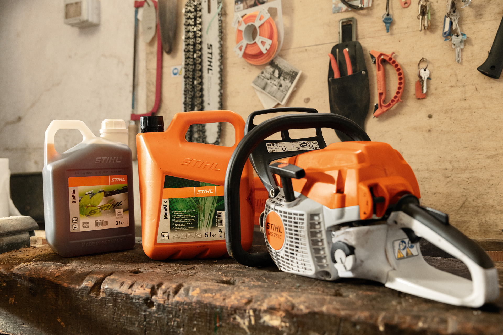 Une tronçonneuse STIHL MS 261 C-BE avec réservoir à ouverture facile posée près de bidons MotoMix et BioPlus