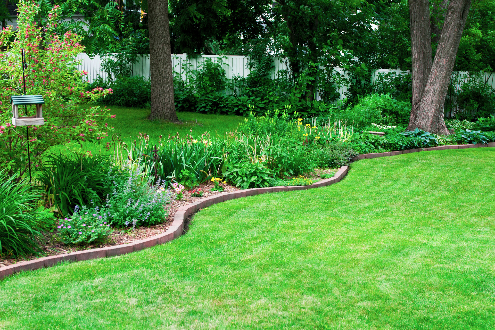 Parterre de jardin avec une bordure en pierres faite maison sur une pelouse verte