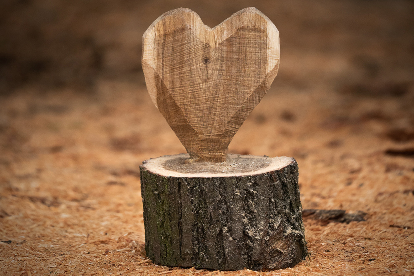 Een houten hart staat op de grond tussen houtspaanders