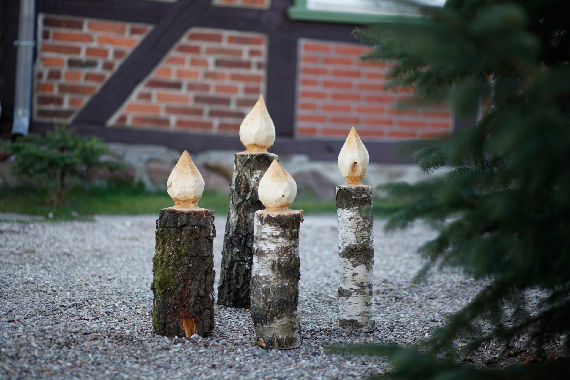 Quatre bougies en bois sur un chemin à côté d’un sapin