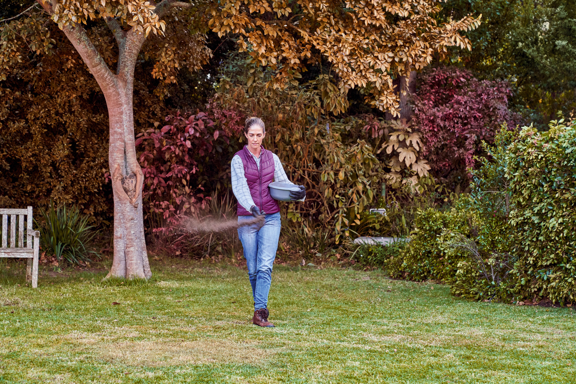 Une femme répand de l’engrais dans son jardin.