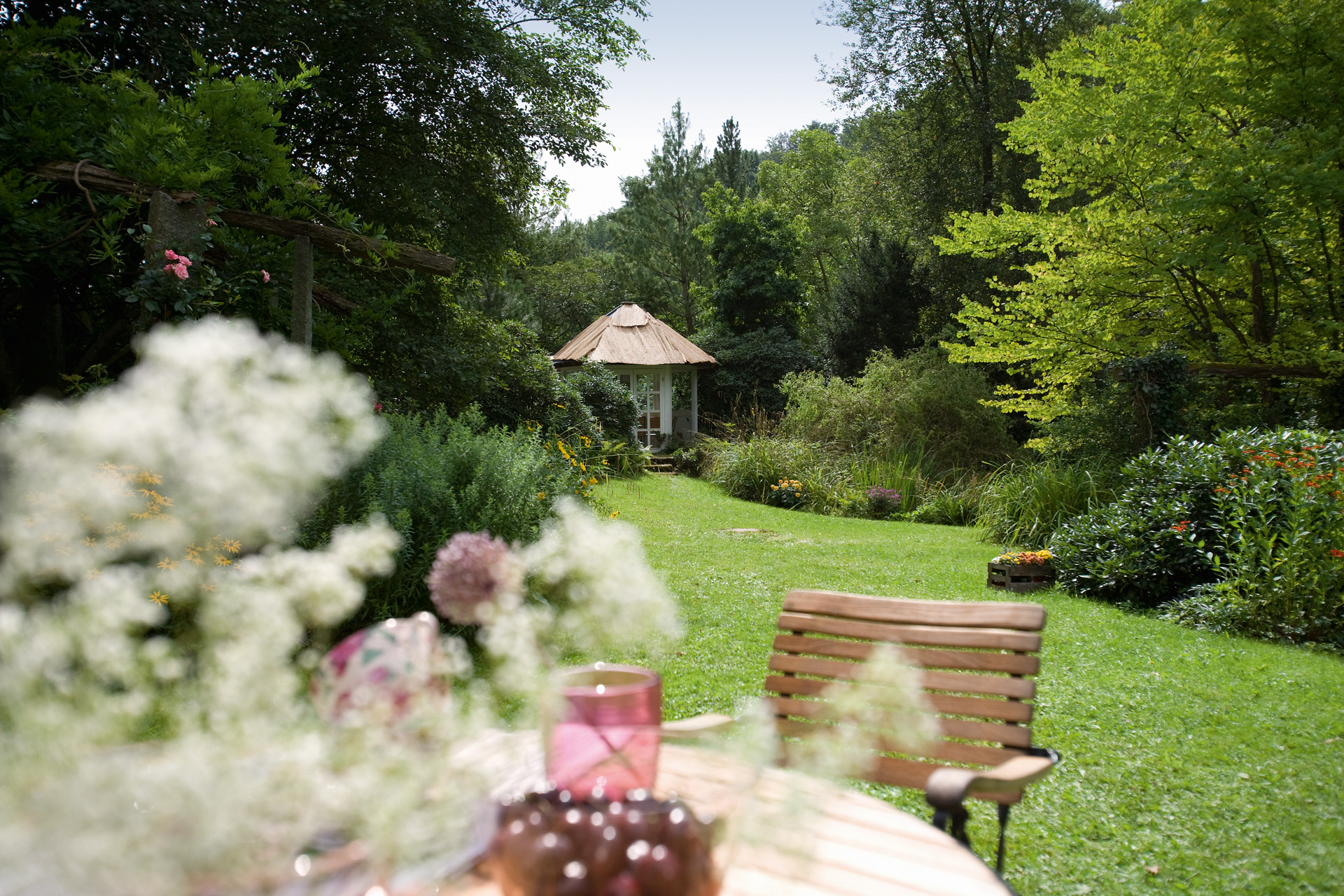 Tuinonderhoud in groene tuin met stoel op de voorgrond en tuinhuisje op de achtergrond