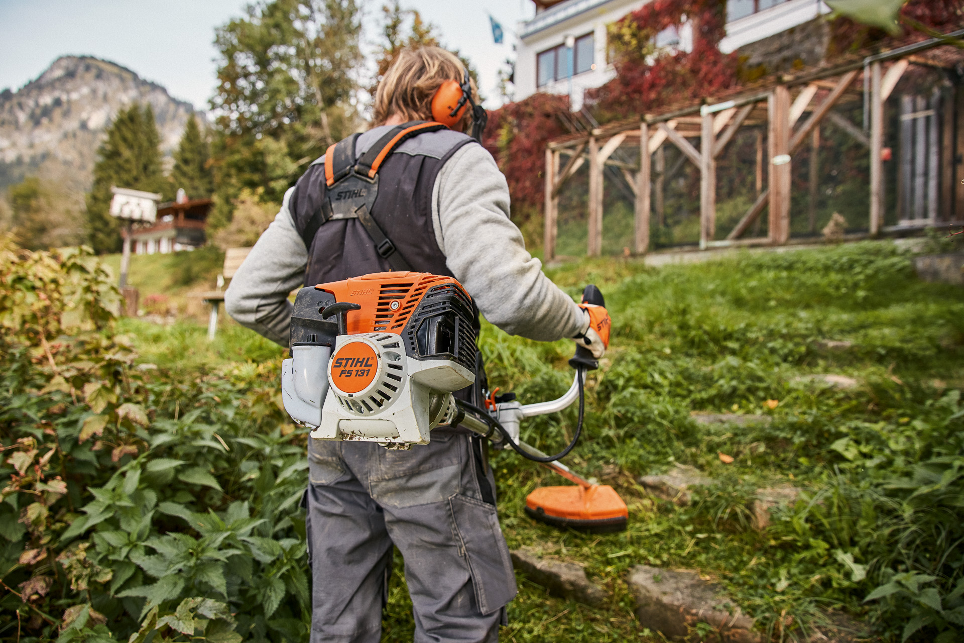 Hellend terrein voor een huis wordt met de STIHL benzinekantenmaaier FS 131 met 4-MIX®-motor gemaaid