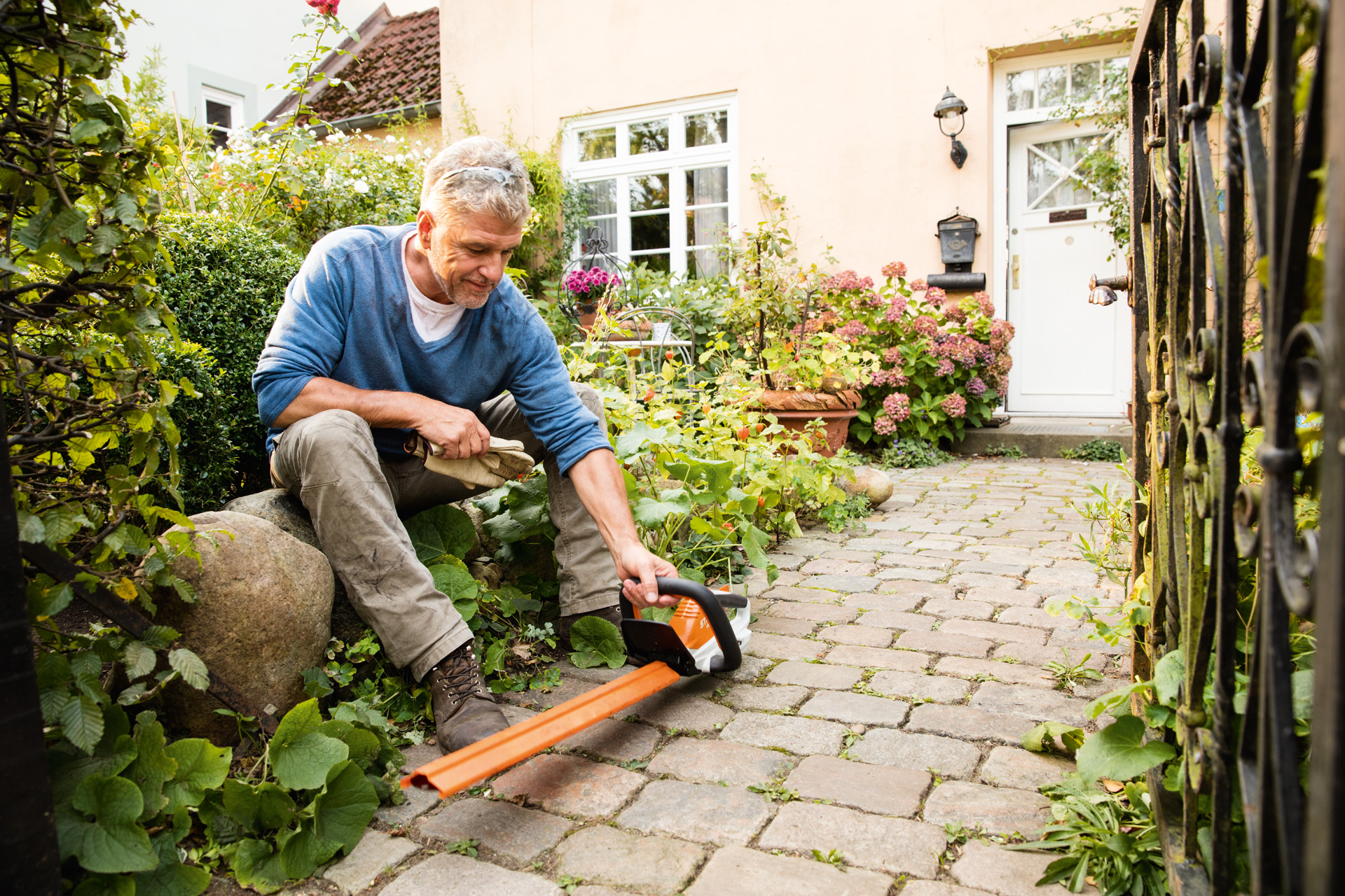 Man met STIHL accuheggenschaar HSA 45 van de AI lijn voor een huis