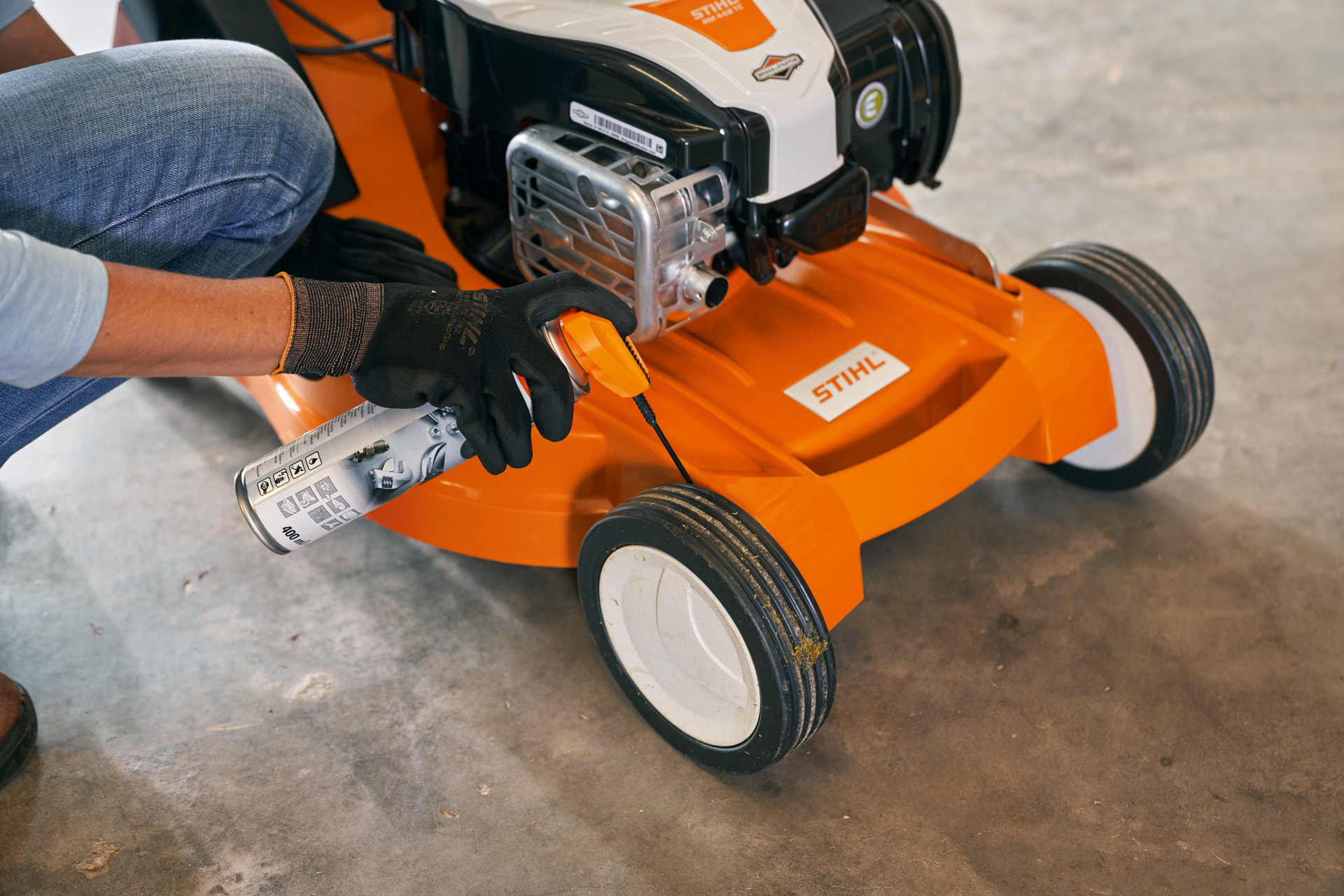 Une femme range sa tondeuse thermique STIHL RM 448 TC dans un garage 