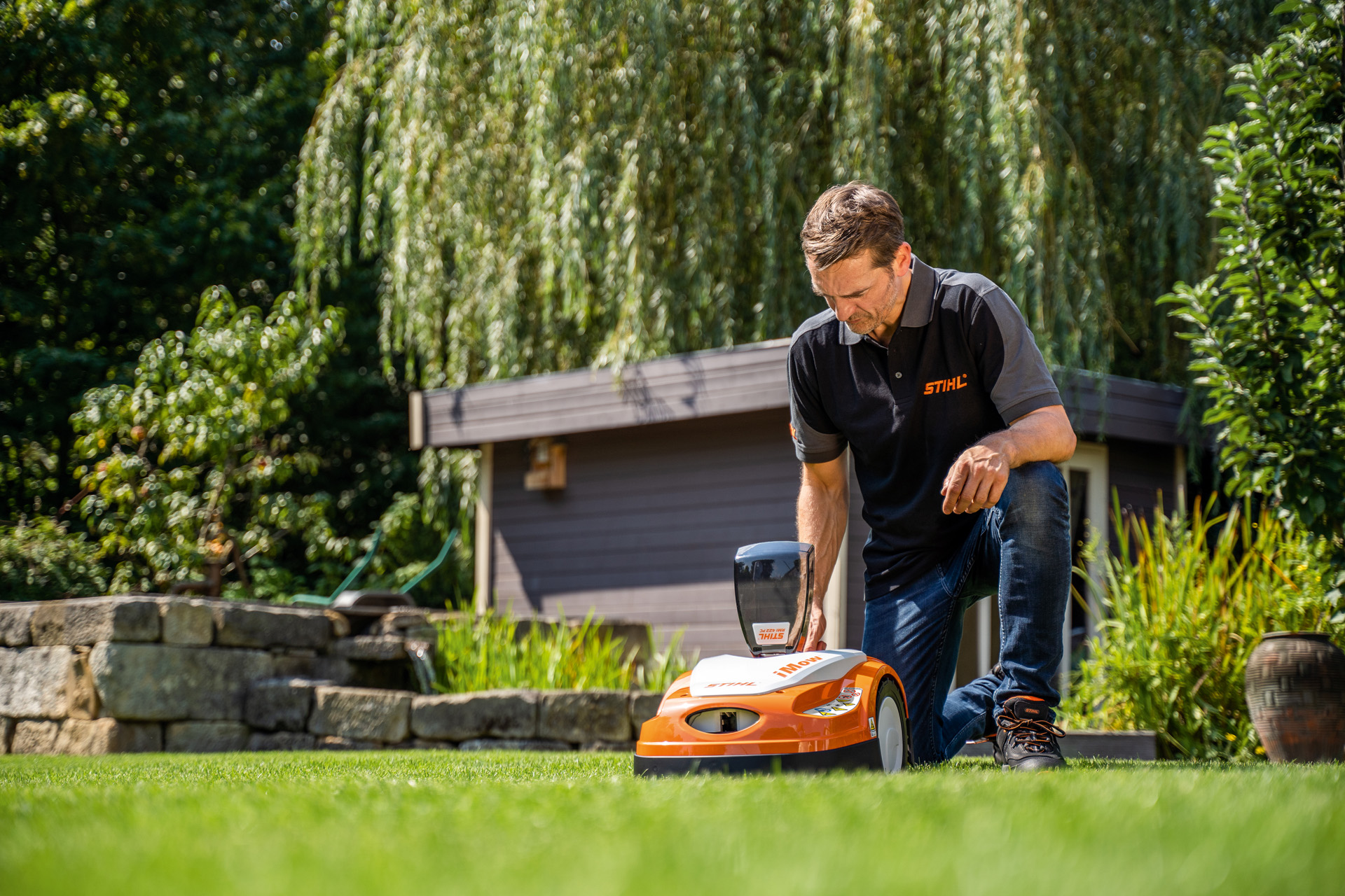 STIHL dealer programmeert het maaischema van een STIHL iMOW robotmaaier in een tuin