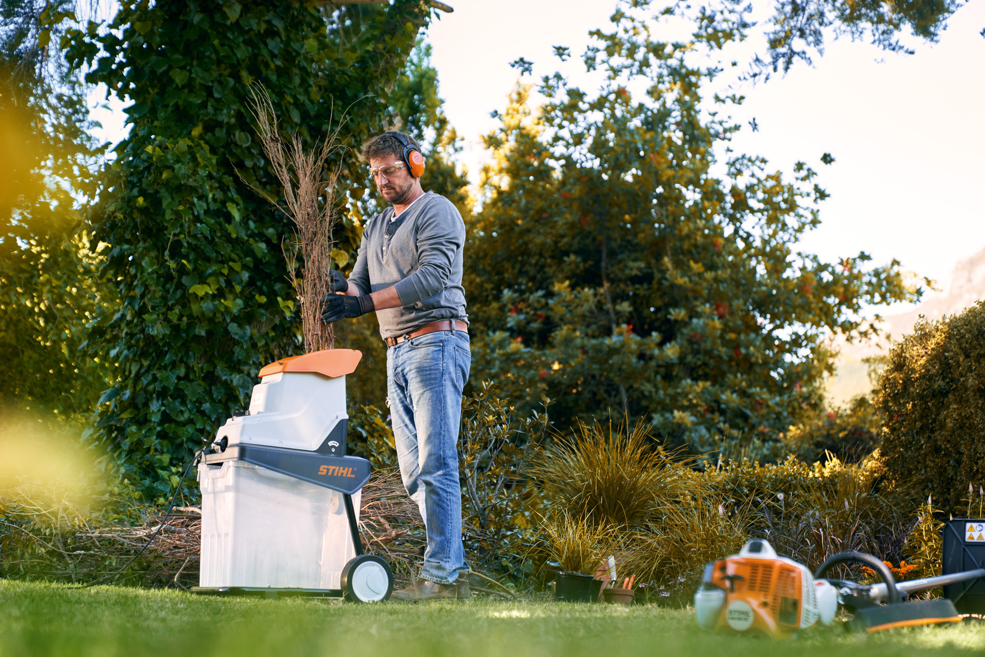 Een man die snoeisel in een STIHL GHE 140 L elektrische hakselaar doet