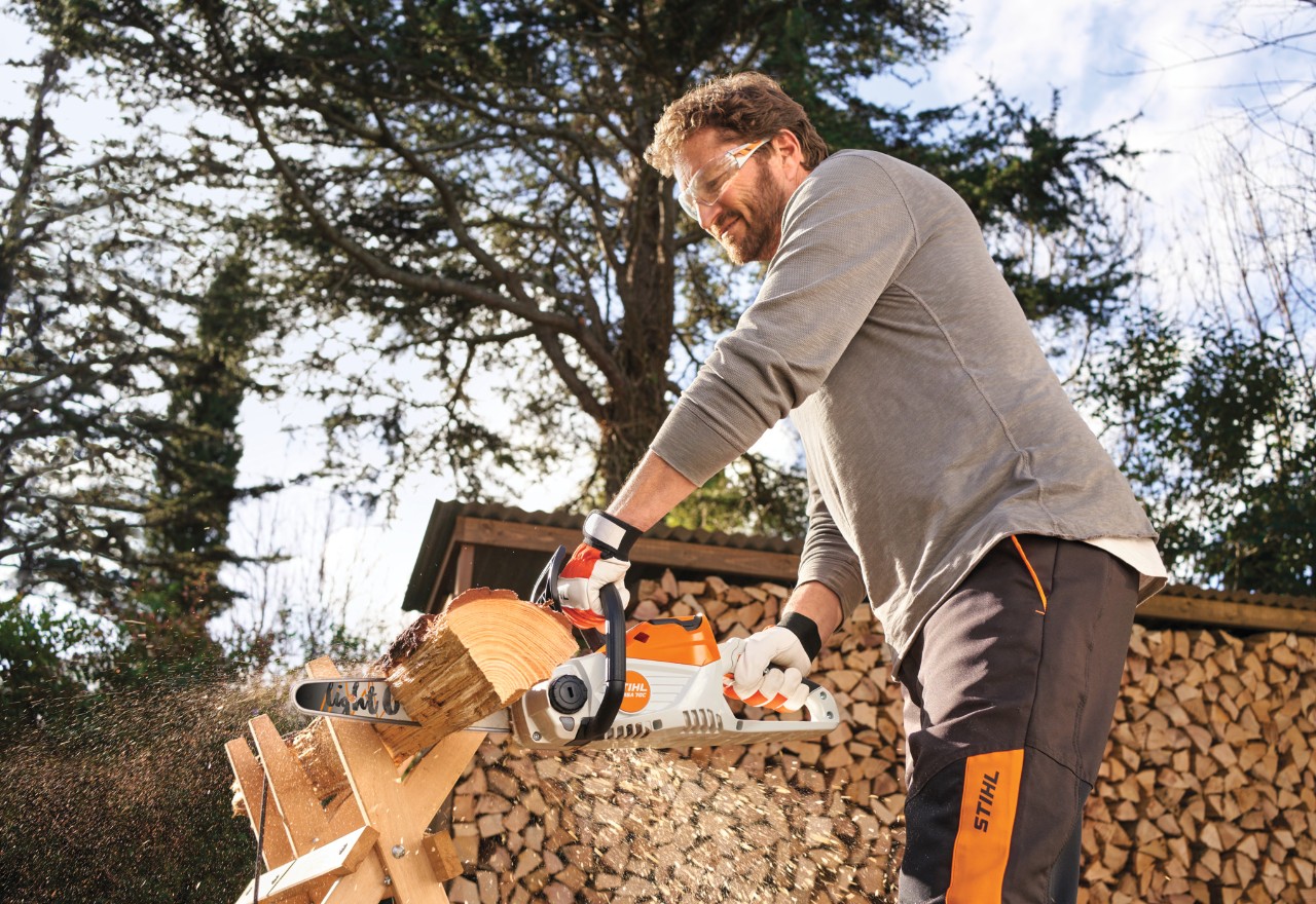 Un homme utilise la STIHL MSA 70 pour couper du bois dans le jardin.