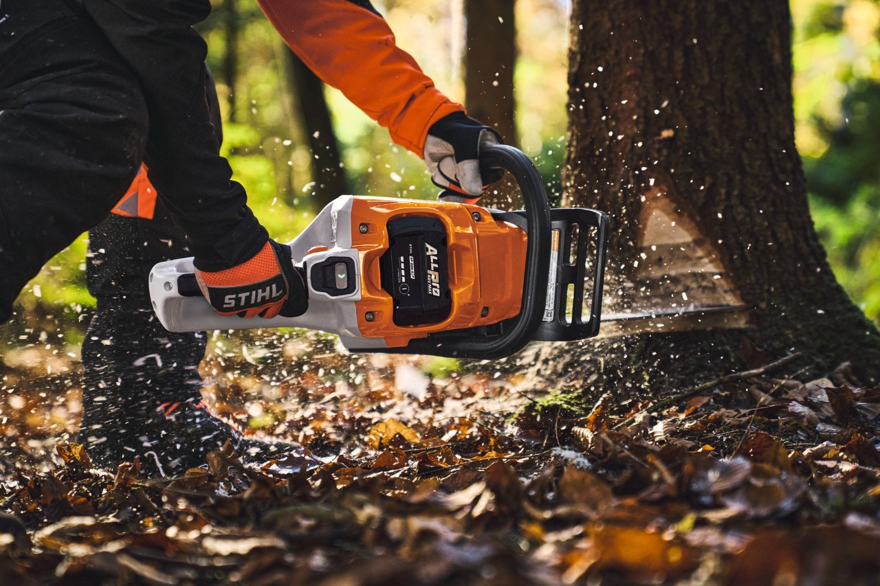 Un professionnel du bois abat des arbres en forêt à l'aide d'une tronçonneuse sans fil de type STIHL MSA260 et d'une batterie ALLPRO.