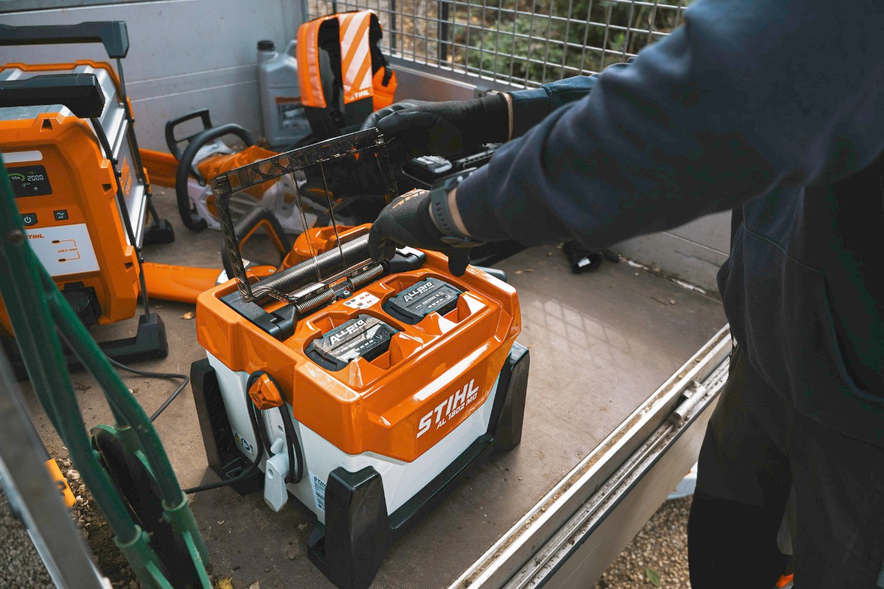 Un homme insère une batterie ALLPRO dans un chargeur rapide