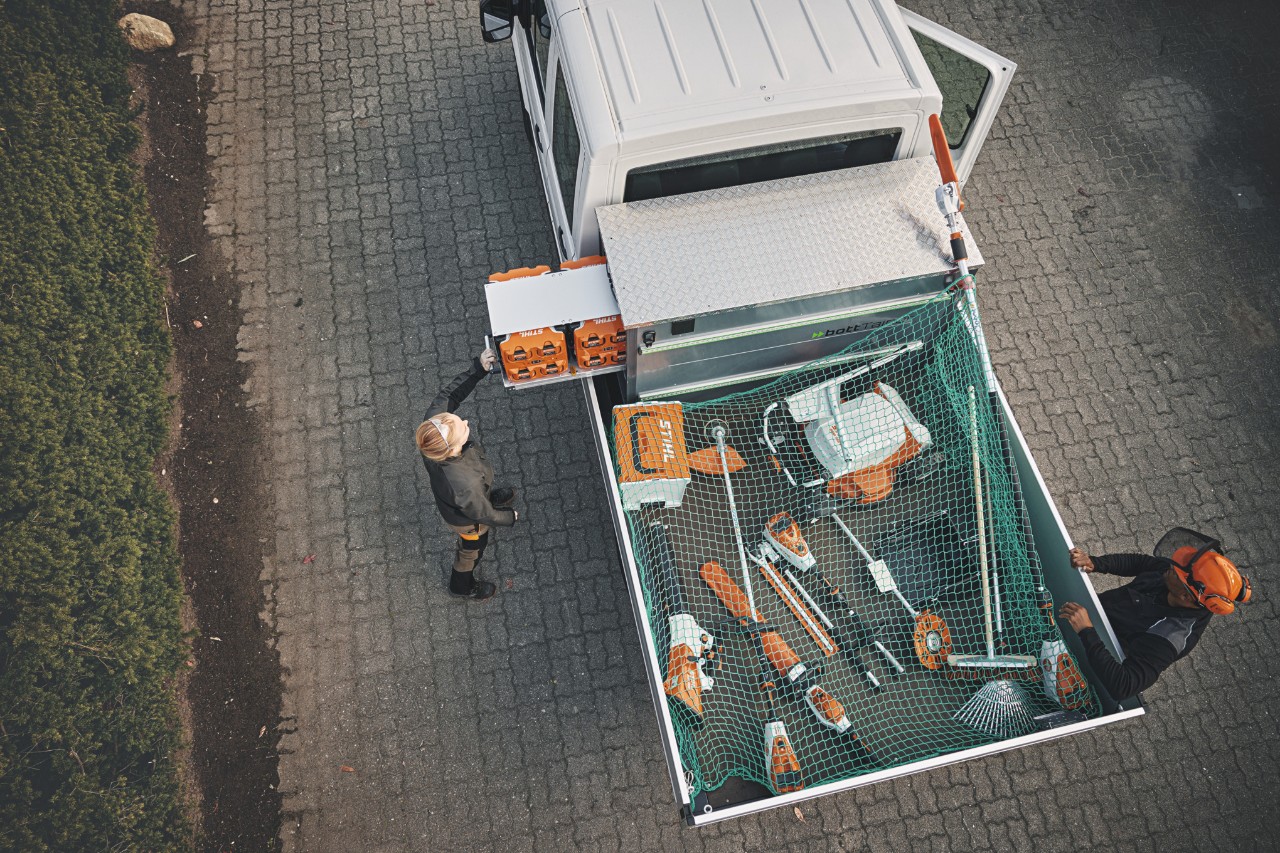 Deux professionnels STIHL en vue aérienne sur un véhicule chargé du bottTainer et d’outils à batterie STIHL.