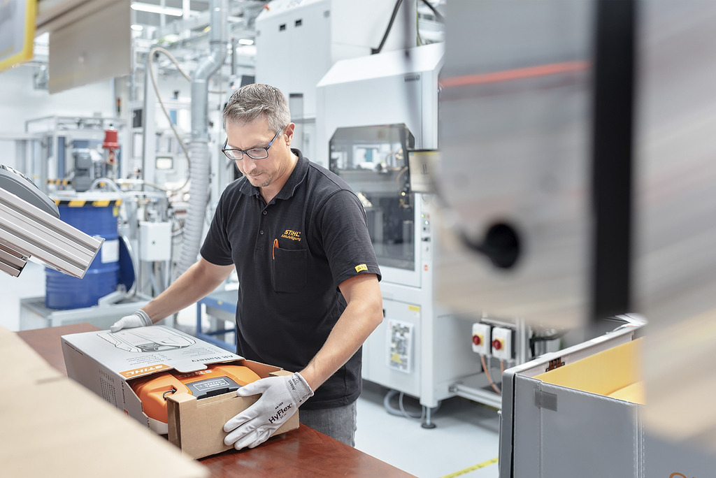 Een medewerker van een accufabriek verpakt een STIHL accumachine in een kartonnen doos.