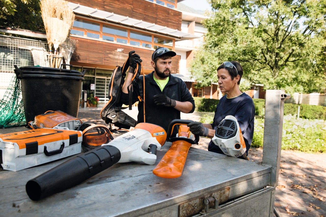 Iemand zit met een laptop aan een bureau in een werkplaats.