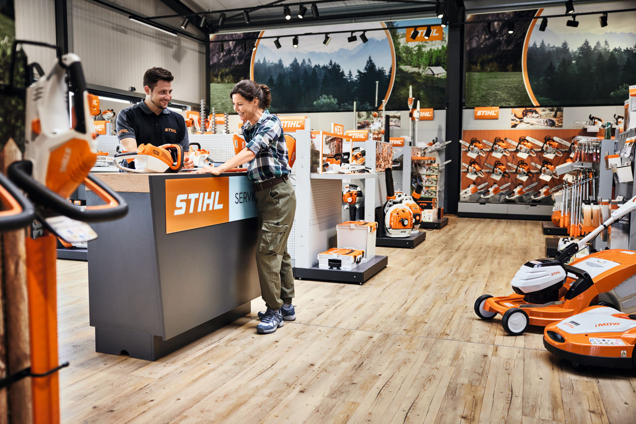 Een vrouw krijgt advies van een man aan de servicebalie bij een STIHL-dealer