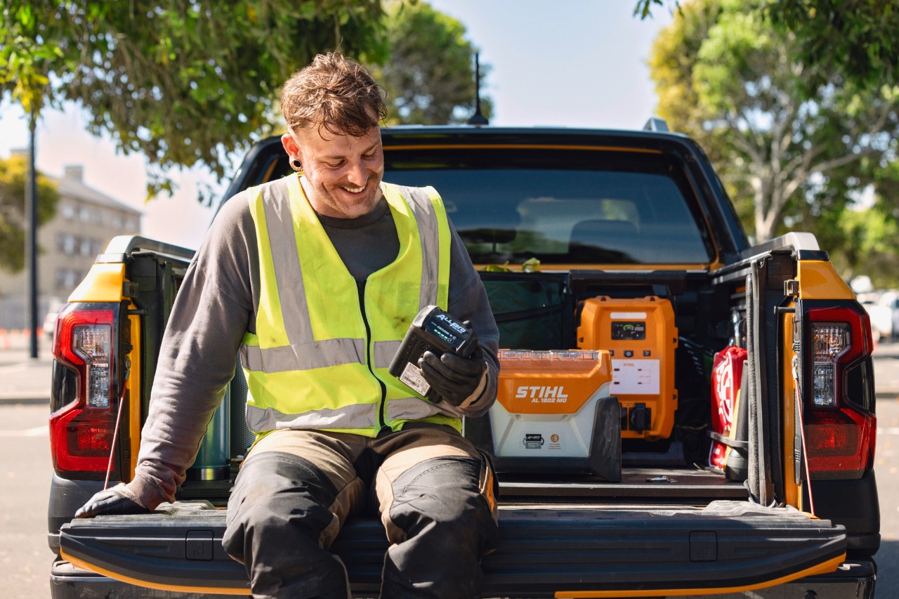 Een werkende man die een ALLPRO-batterij op een vrachtwagen houdt