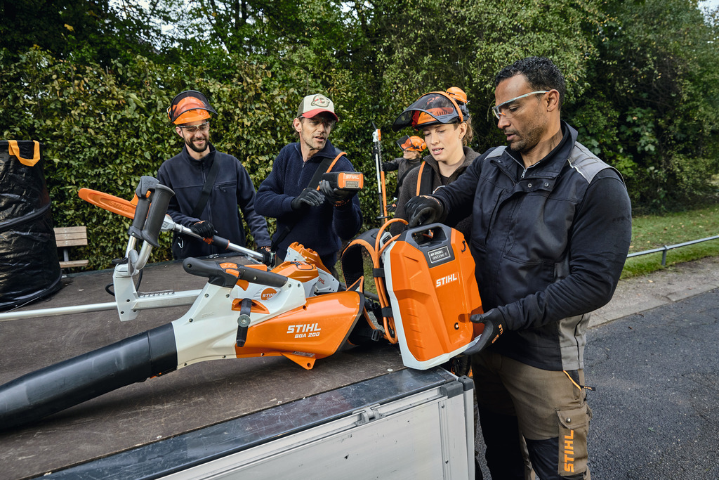 Een team van landschapsarchitecten laadt hun professionele accu-aangedreven STIHL-apparatuur uit de laadruimte van een voertuig.